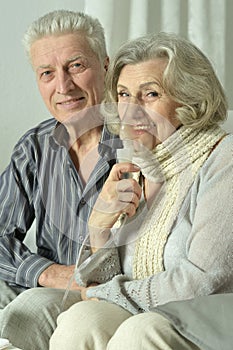 An elderly couple is sick and uses an inhaler