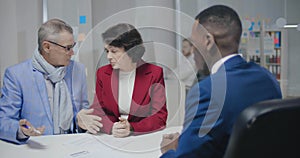 An elderly couple signing papers in a notary`s office,