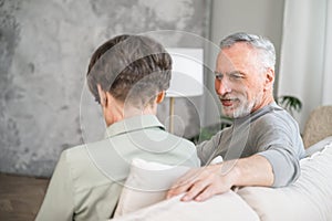 elderly couple sitting on couch and have conversation