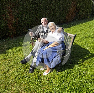 Elderly couple sitting in their garden on a bench