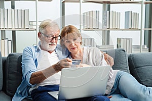 Elderly couple sitting using laptop to shop online with credit card