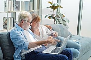 Elderly couple sitting using laptop to shop online with credit card