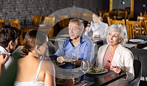 Elderly couple spending time with young friends in restaurant