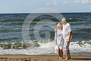 An elderly couple stand hugging on the beach by the sea, look at each other, communicate