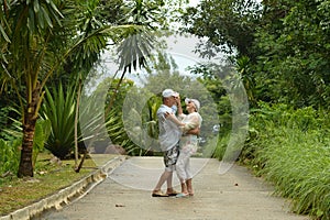 Elderly couple standing embracing in a tropical forest