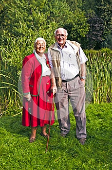 Elderly couple standing hand in hand in their garden