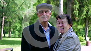 An elderly couple strolling peacefully in the park. A man and woman enjoying a leisurely walk amidst nature.