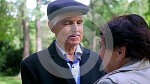 An elderly couple strolling peacefully in the park. A man and woman enjoying a leisurely walk amidst nature.