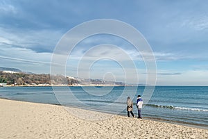 An elderly couple walking along the sea beach at the surf line on a warm sunny winter day