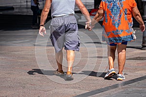 An elderly couple walking by the hand