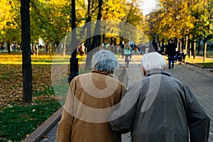 Elderly couple walking in park on autumn day