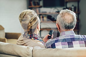 Elderly couple watching television sitting comfortably on a sofa