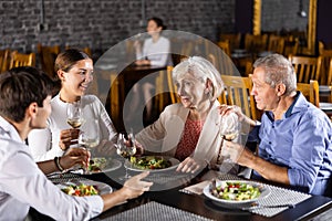 Elderly couple and young couple having dinner in restaurant