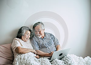 Elderly couples using laptop in bedroom