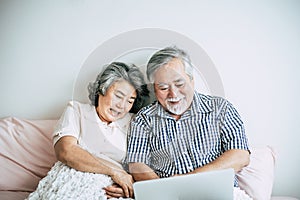 Elderly couples using laptop in bedroom