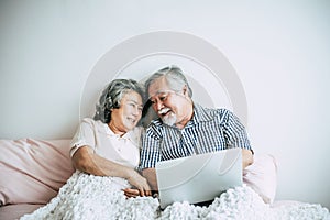 Elderly couples using laptop in bedroom