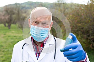 Elderly doctor holding asthma inhaler