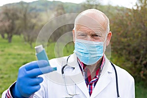 Elderly doctor holding asthma inhaler