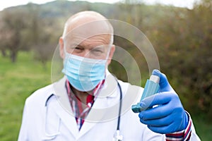 Elderly doctor holding asthma inhaler