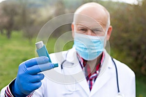 Elderly doctor holding asthma inhaler