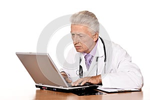 Elderly doctor with a laptop on white background