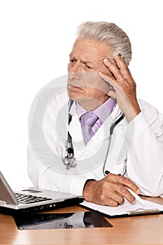 Elderly doctor with a laptop on white background