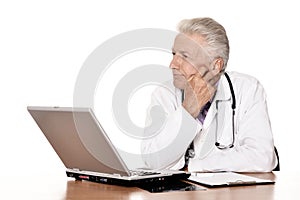 Elderly doctor with a laptop on white background