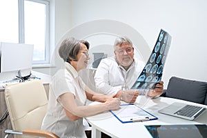 Elderly doctor and patient are studying MRI scans