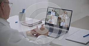 Elderly doctor talking head shot portrait four diverse medical workers in white coats take part in distant talk, engaged