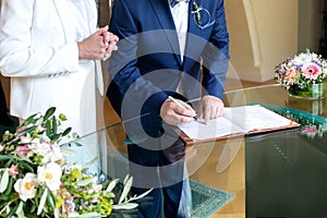 Elderly elegant traditional couple signing marriage agreement at desk. Man& x27;s hand holding pen and signing paper