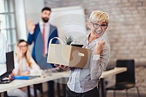 Elderly employee leaving office with box full of belongings.