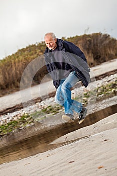 Elderly energetic man running along a beach