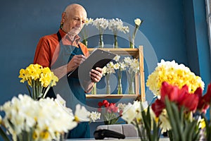 An elderly European smiling flower seller places an order.