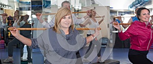 Elderly exercise with gymnastic sticks in modern gym