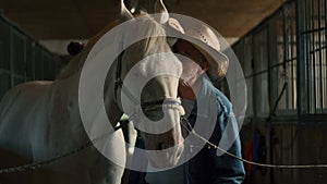 Elderly farmer cleaning horse in stable