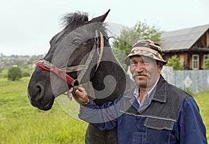 An elderly farmer with his horse in the rain. Old-believer village Visim, Russia.