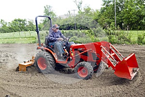 Elderly Farmer Tilling His Garden With A Compact 4x4 Tractor
