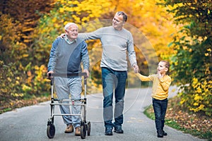 Elderly father, adult son and grandson out for a walk in the park