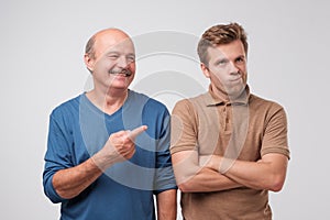 The elderly father laughs at his son. He won the argument. A young man is offended and discouraged by his loss.