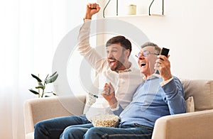 Elderly Father And Middle-Aged Son Watching Sports On TV Indoor