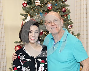 Elderly father and teenage daughter in front of a Christmas Tree