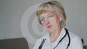 an elderly female doctor is talking via video link with her patient