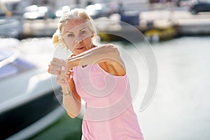 Elderly female doing shadow boxing outdoors. Senior woman doing sport in a coastal port