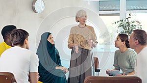 Elderly female manager holds round table meetings for employees of different nationalities