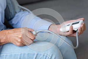 Elderly female patient use electronic tonometer at home