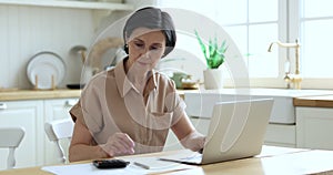 Elderly female use calculator manage budget, pay bills online