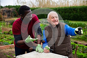Elderly gardener chatting with African friend