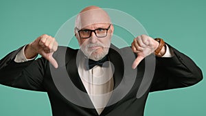 Elderly Gentleman in Black Jacket Giving Thumbs Up and Down on Teal Background