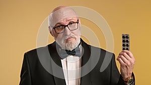 An elderly gentleman showing a blister pack of pills, indicating their