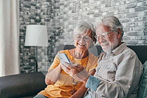 Elderly grandfather and grandmother spend time having fun using smartphone apps, middle-aged wife enjoy online entertainments,